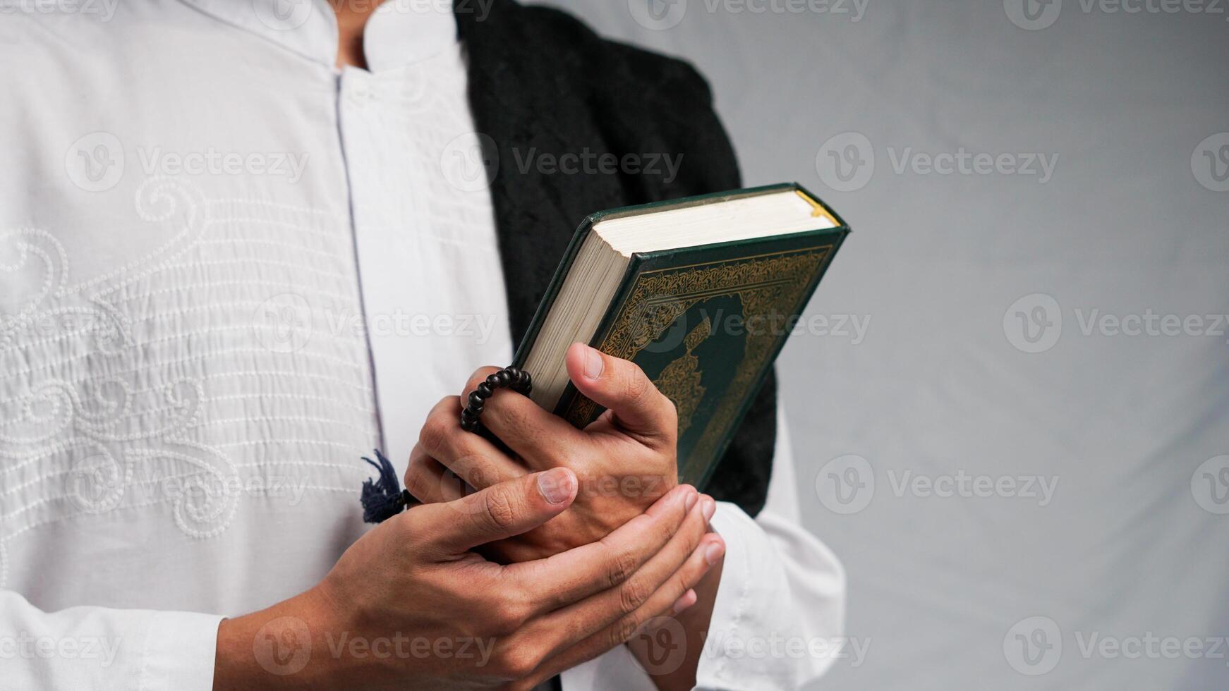 man holding the Quran with prayer beads in his hand photo