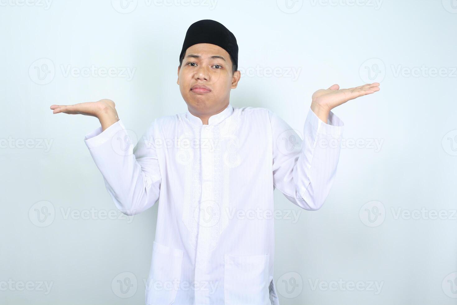 confused asian muslim man raising arm to presenting empty space isolated on white background photo