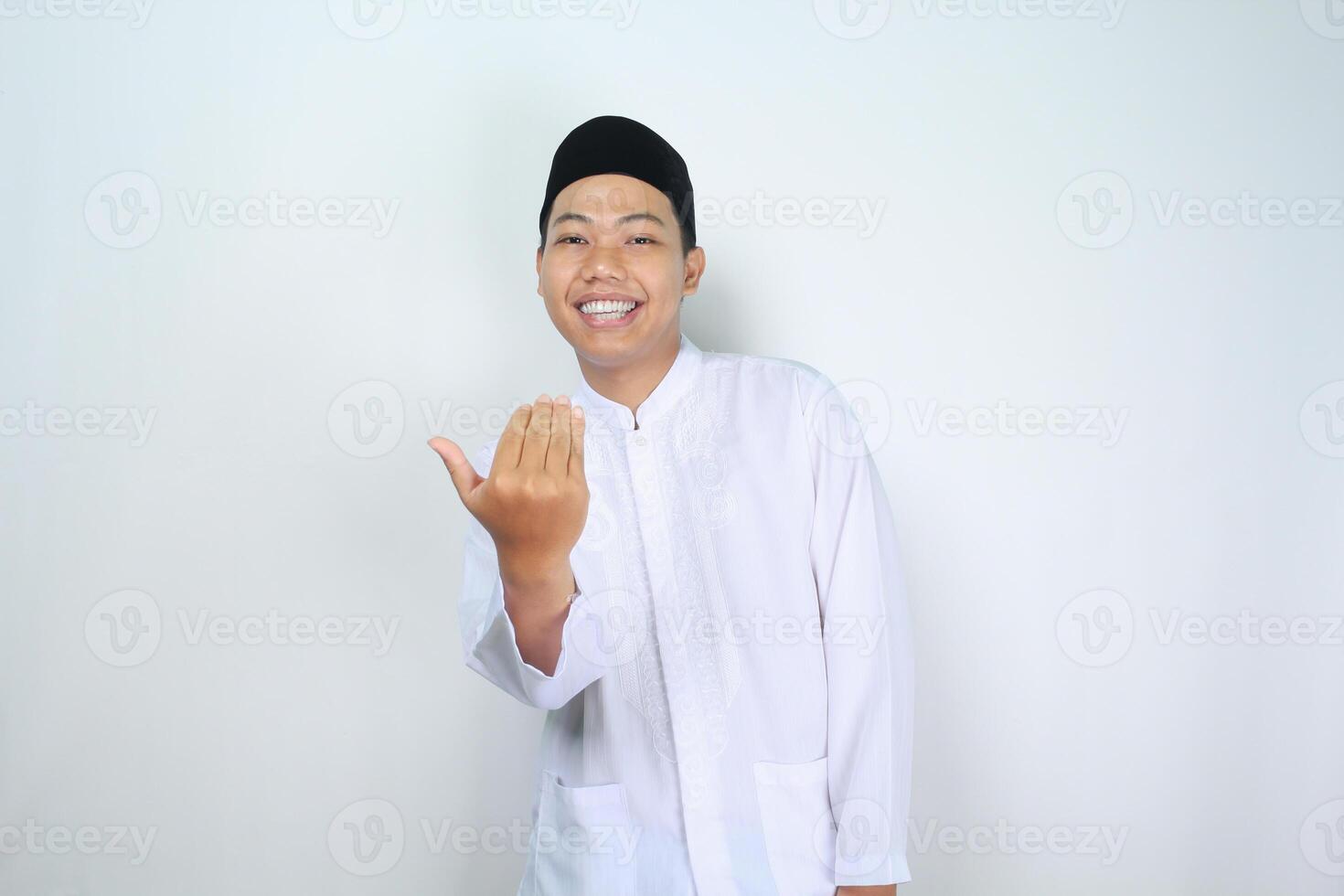 smiling muslim asian man show inviting gesture with looking at camera isolated on white background photo