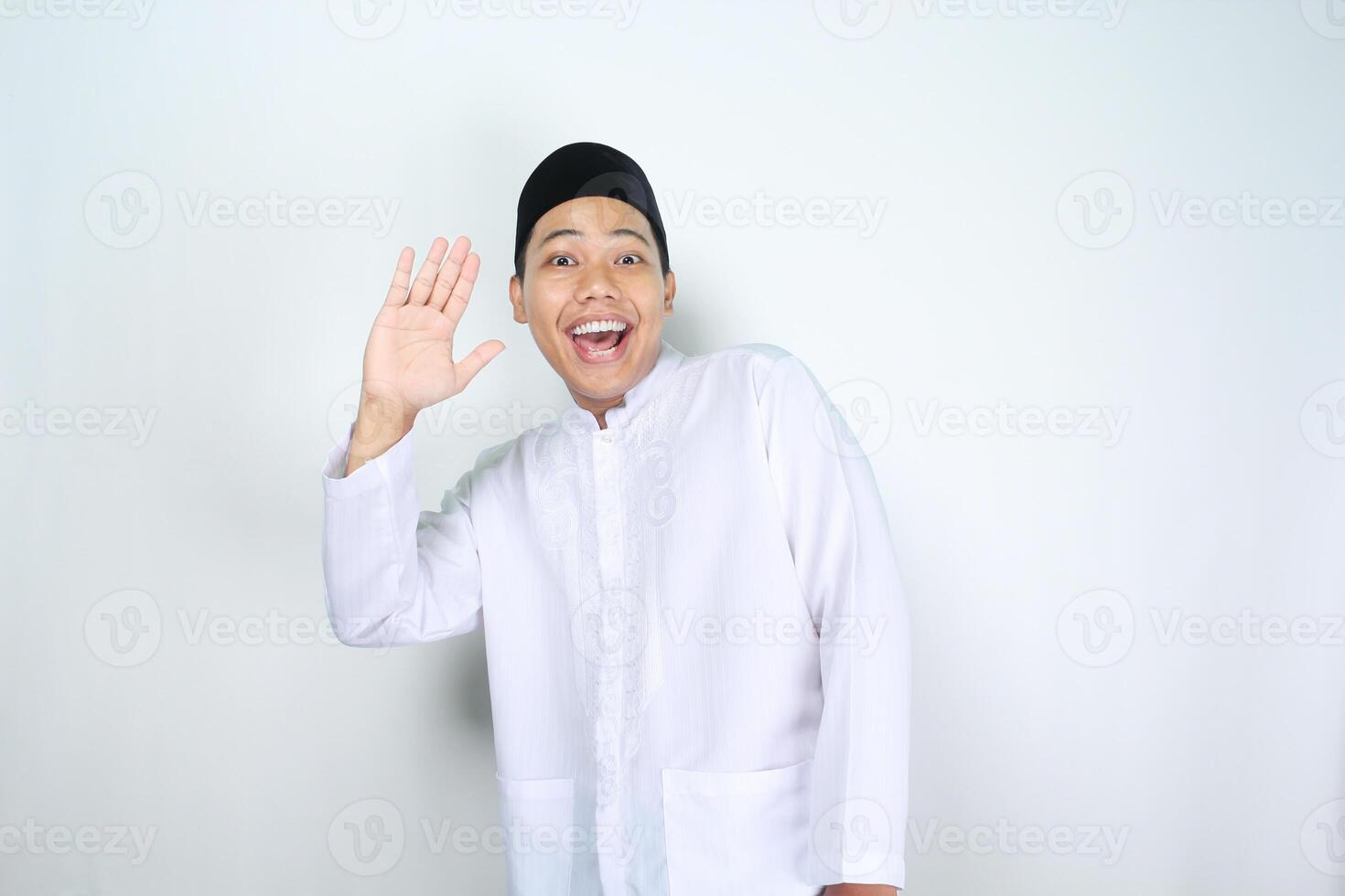 funny asian muslim man show surprised expression while waving hand say hello isolated on white background photo
