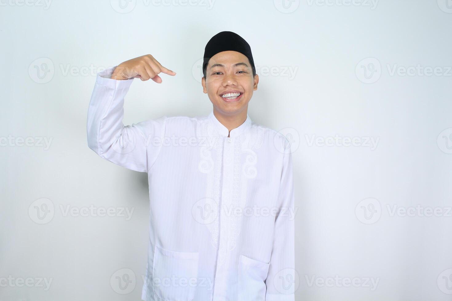 alegre musulmán asiático hombre señalando a él yo con sonriente a cámara, espectáculo sus yo gesto, aislado en blanco antecedentes foto