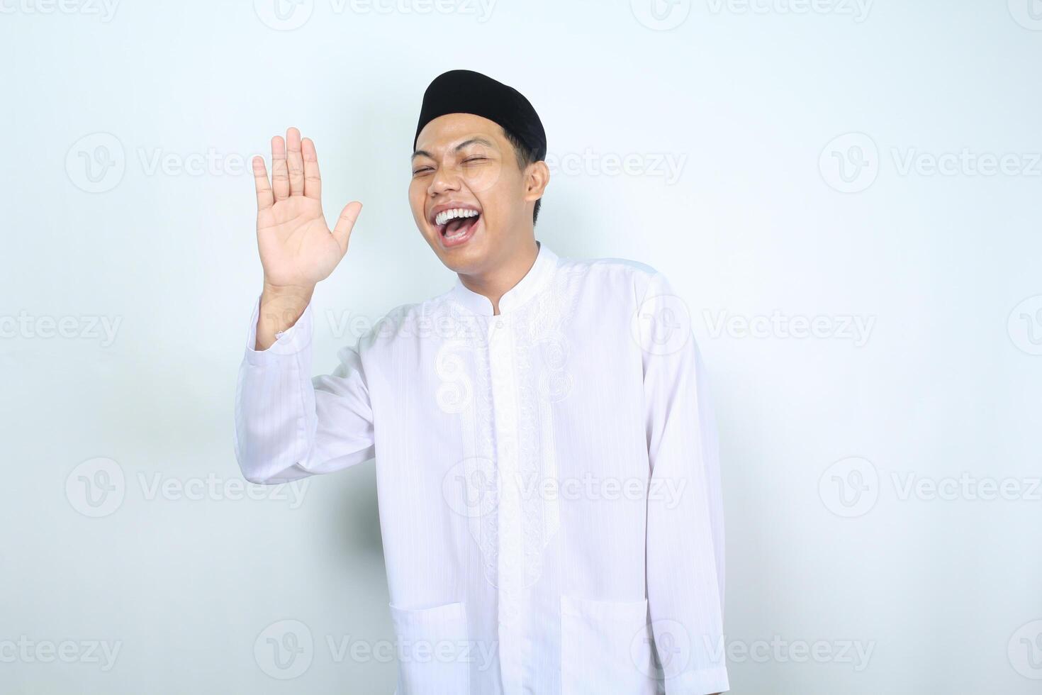 laughing asian muslim man waving hand show hi gesture isolated on white background photo