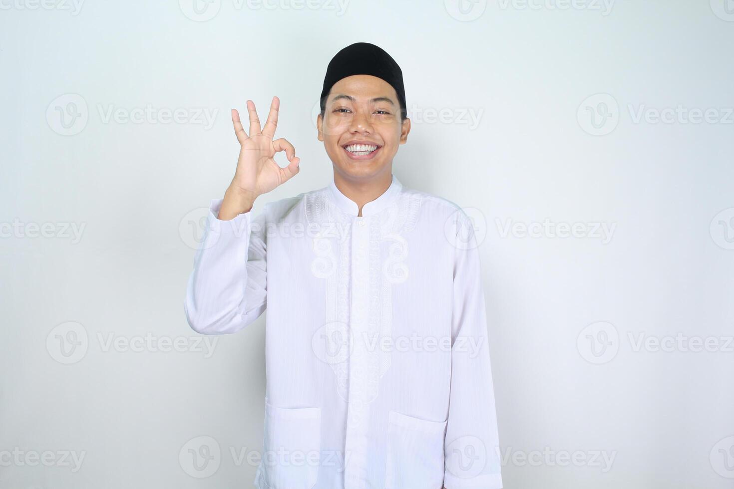 sonriente asiático hombre musulmán espectáculo Okay señales aislado en blanco antecedentes foto