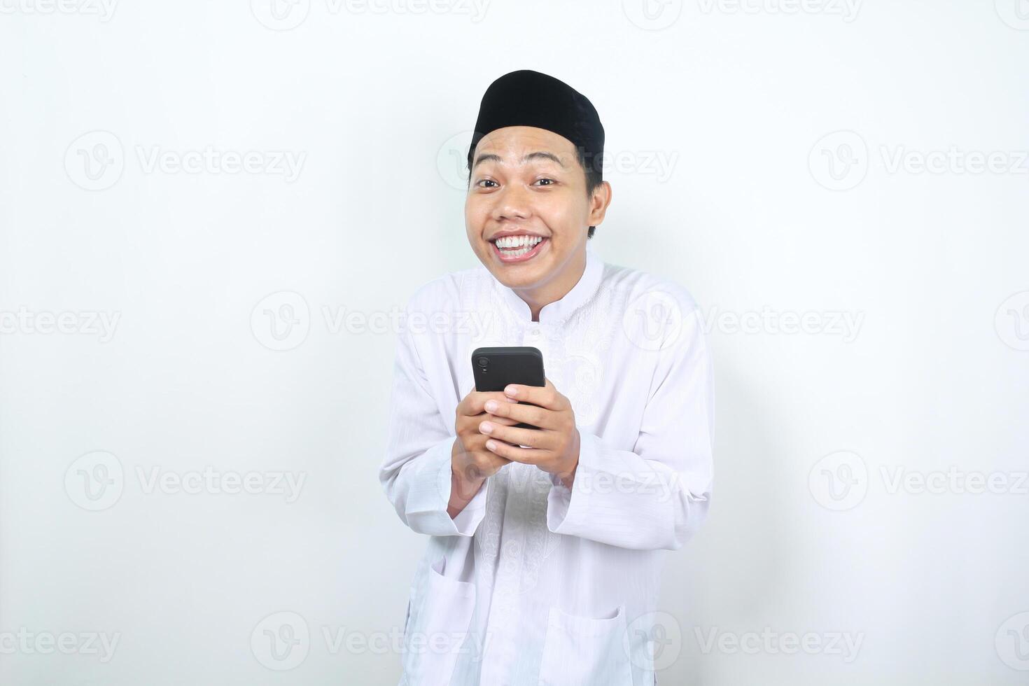 funny and amazed face of muslim asian man holding phone with looking at camera photo