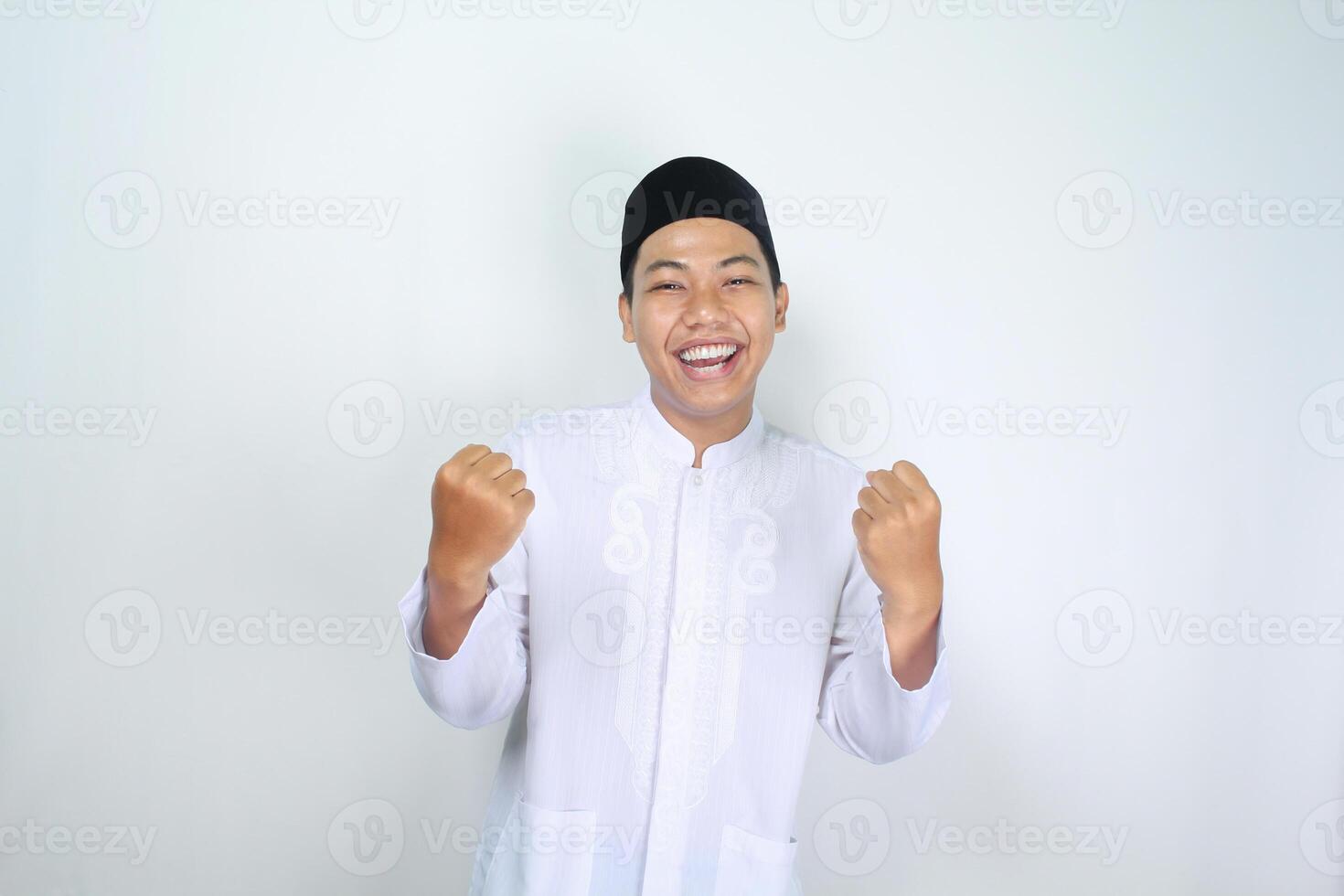 happy muslim asian man raising fist show victory gesture in eid mubarak celebration isolated on white background photo