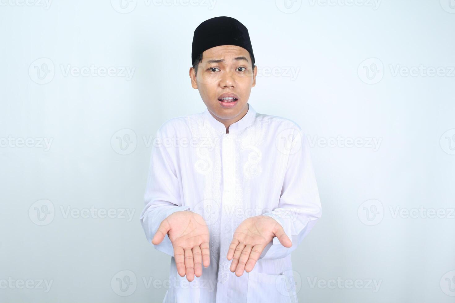 confused asian muslim man presenting empty palm at camera isolated on white backround photo