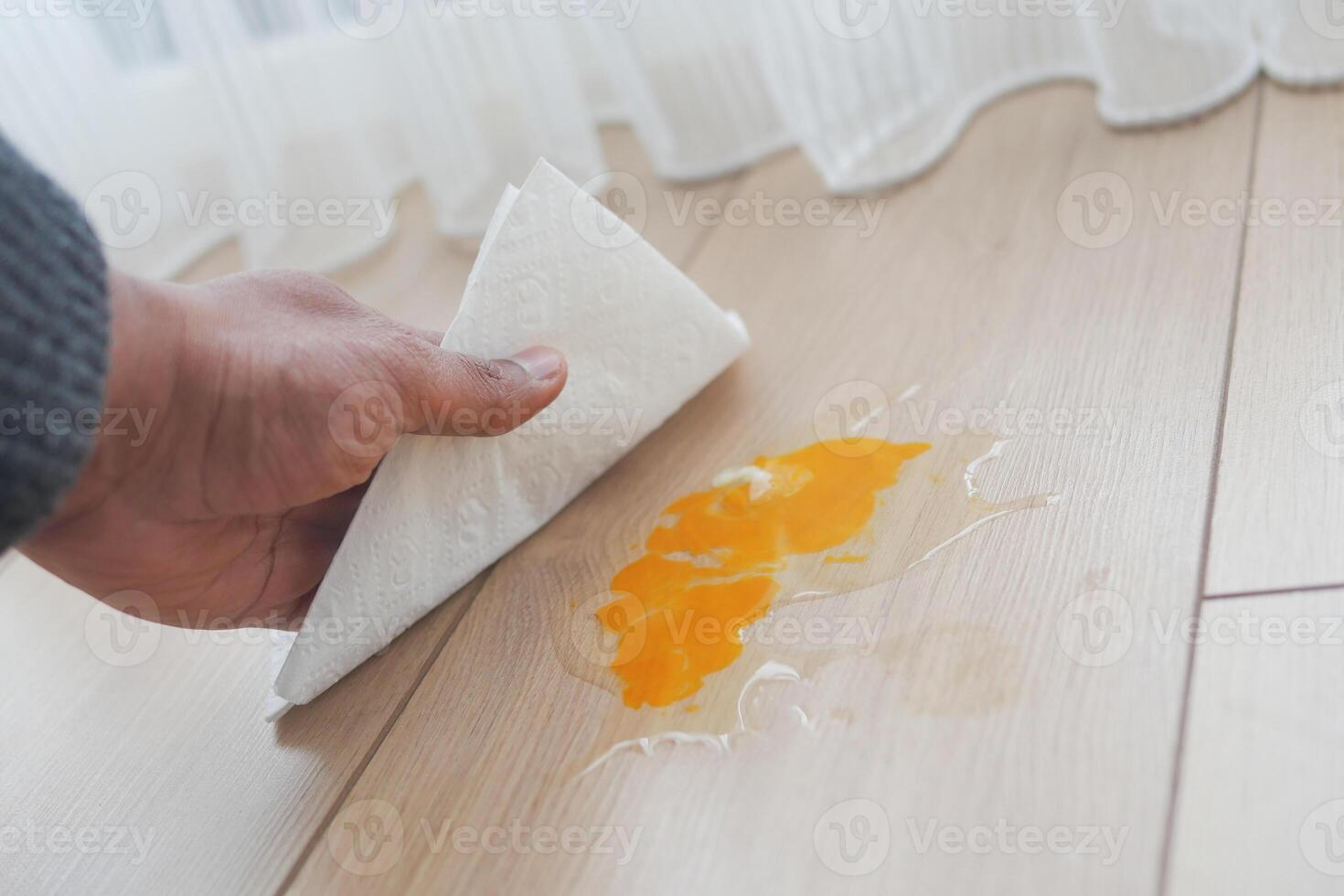 A man's hand washing the floor with a tissue cleaning egg spill photo