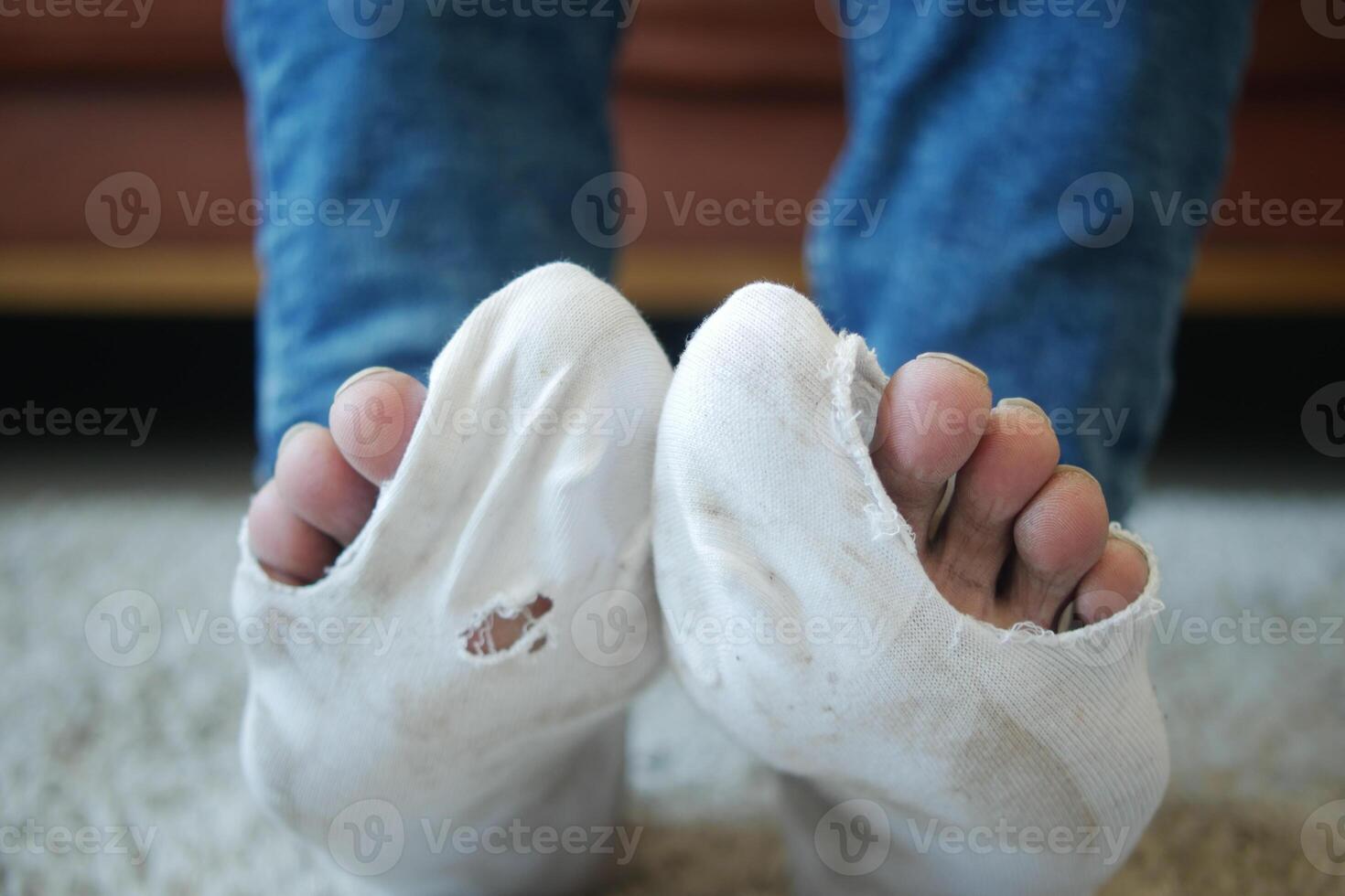 men feet with dirty socks while sitting on sofa photo