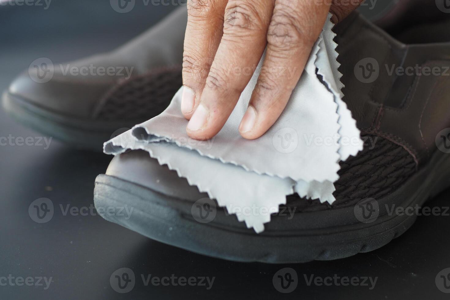 Men wipes his leather shoes with a wet cloth photo