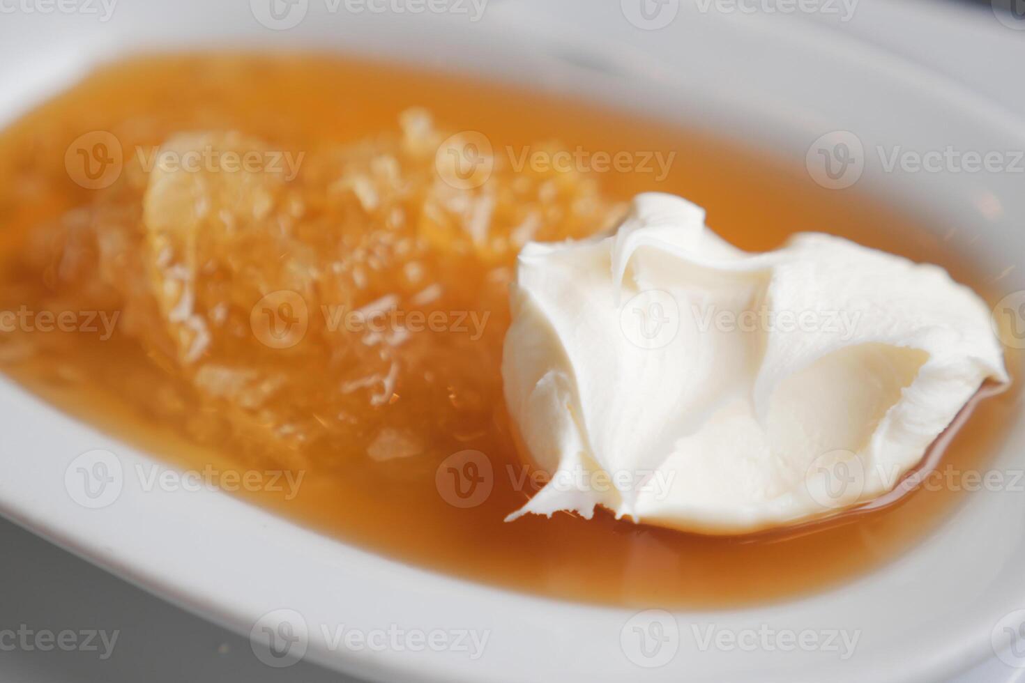 butter cream and honey in a bowl on table . photo