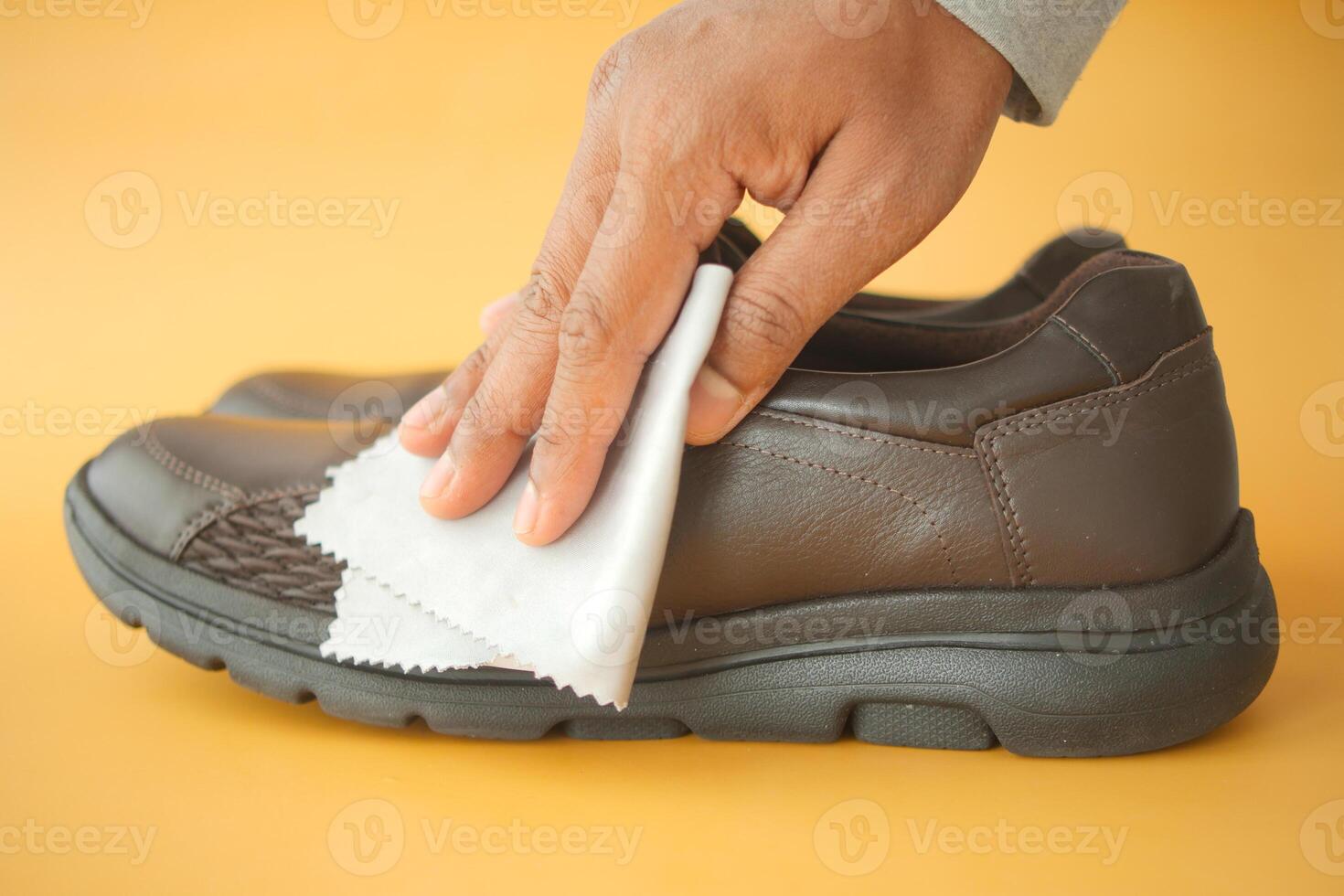 Men wipes his leather shoes with a wet cloth photo