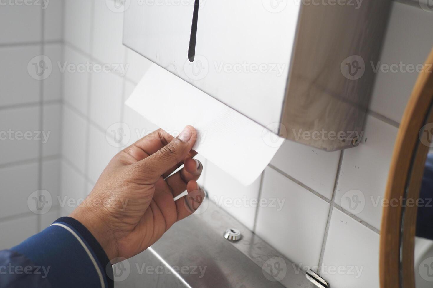 a person is using a paper towel dispenser in a bathroom photo