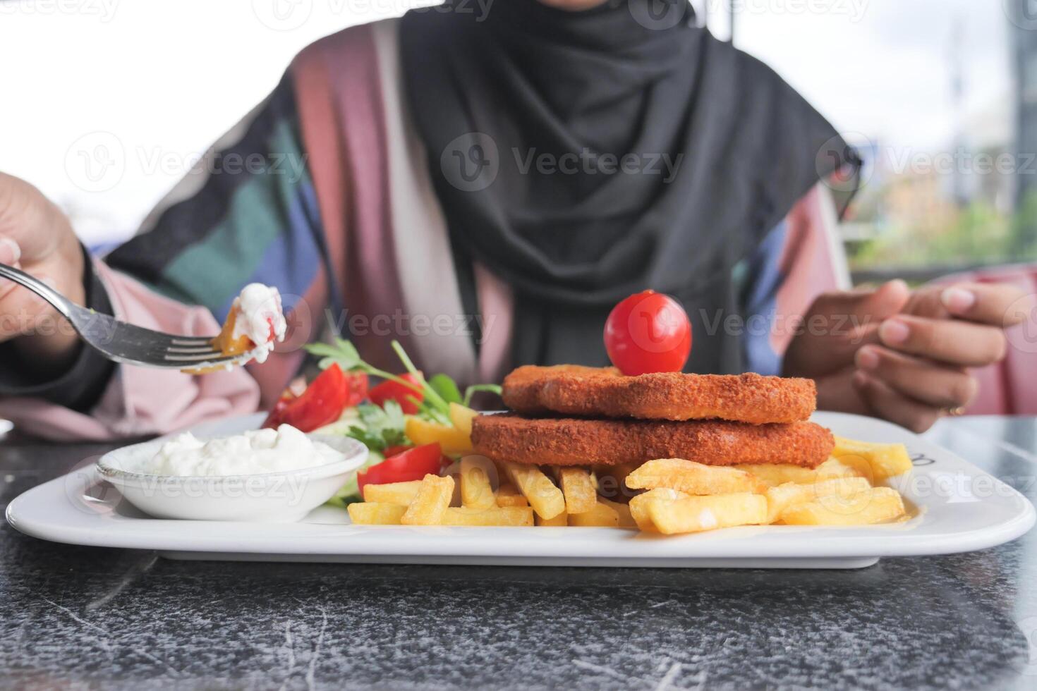 women eating Chicken schnitzel served with potato chips photo