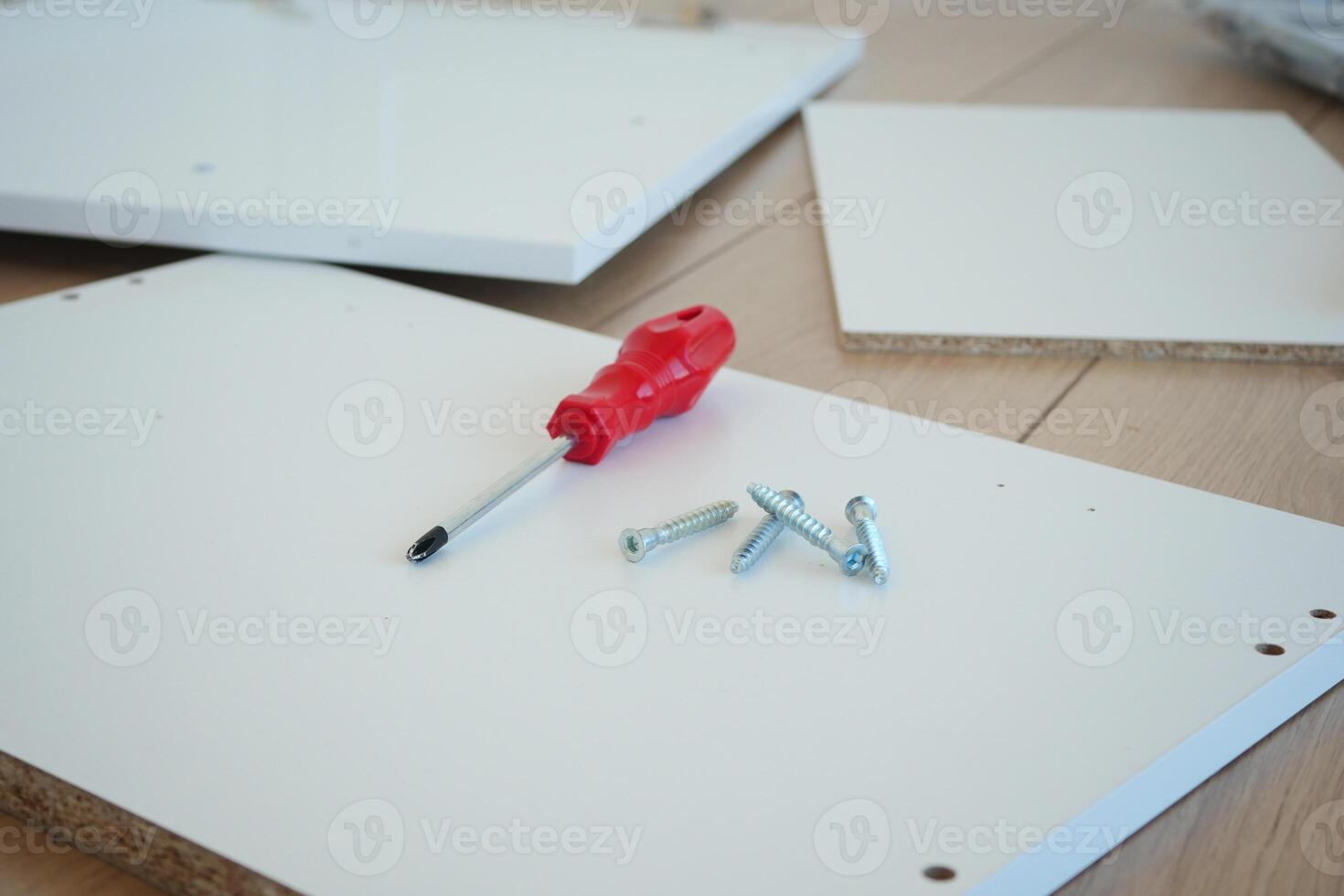 Screwdriver and screws resting on a sturdy piece of wood photo