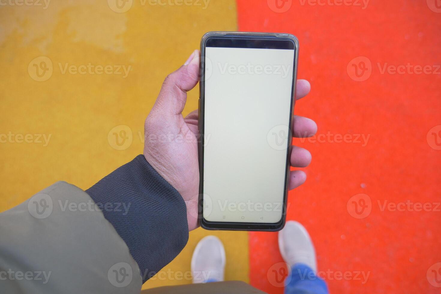 pov of hand holding a smart phone with empty screen on color background photo