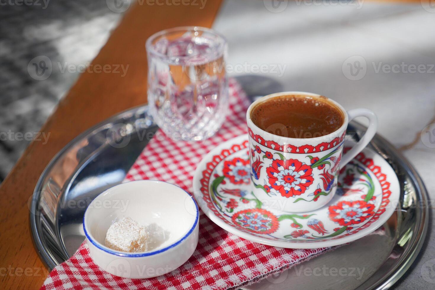 a cup of turkish coffee served with water and turkish delight on table photo