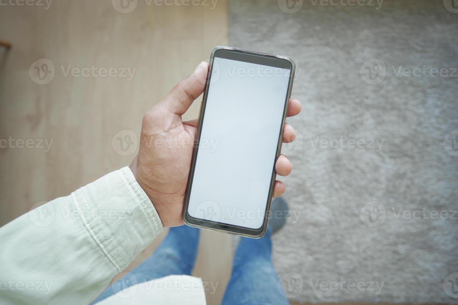 pov shot of holding smart phone with white screen at home photo