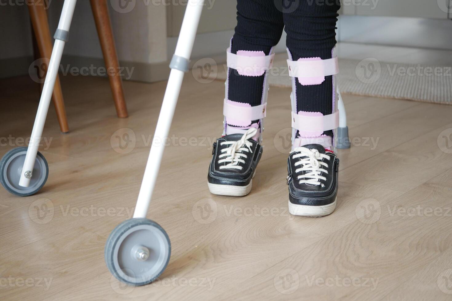 child with walking frame and knee orthosis outdoor photo