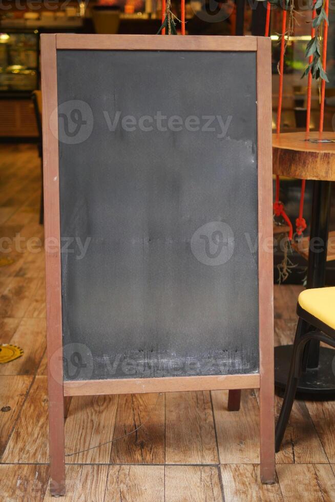 Empty wooden blackboard mockup standing outdoors in front of cafe photo