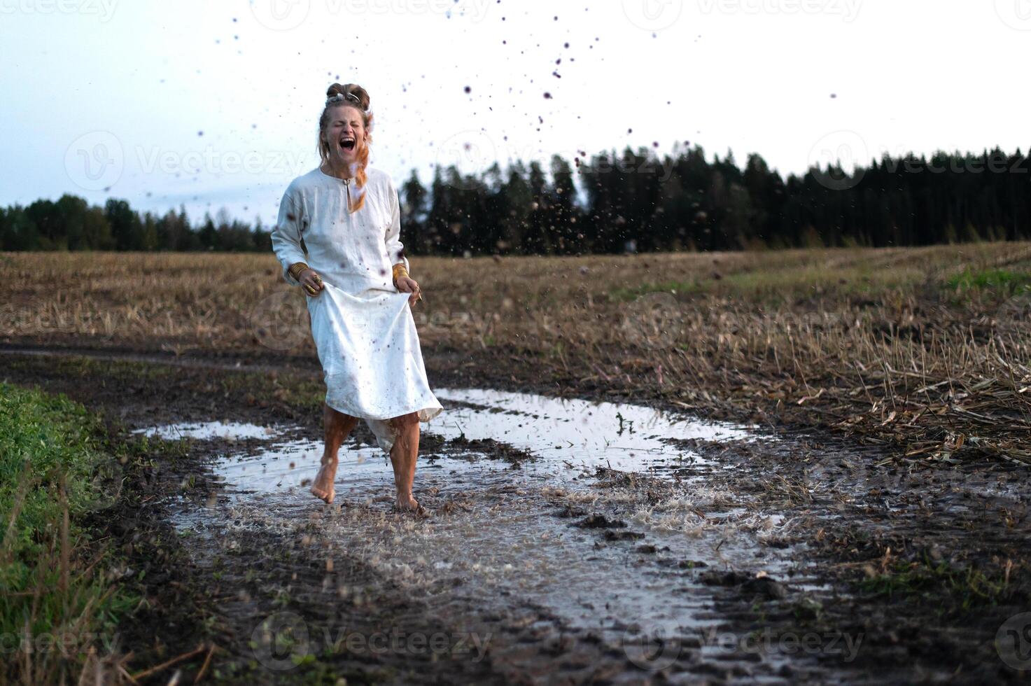 Cheerful young  woman with reeds dances in colored smoke in a field photo