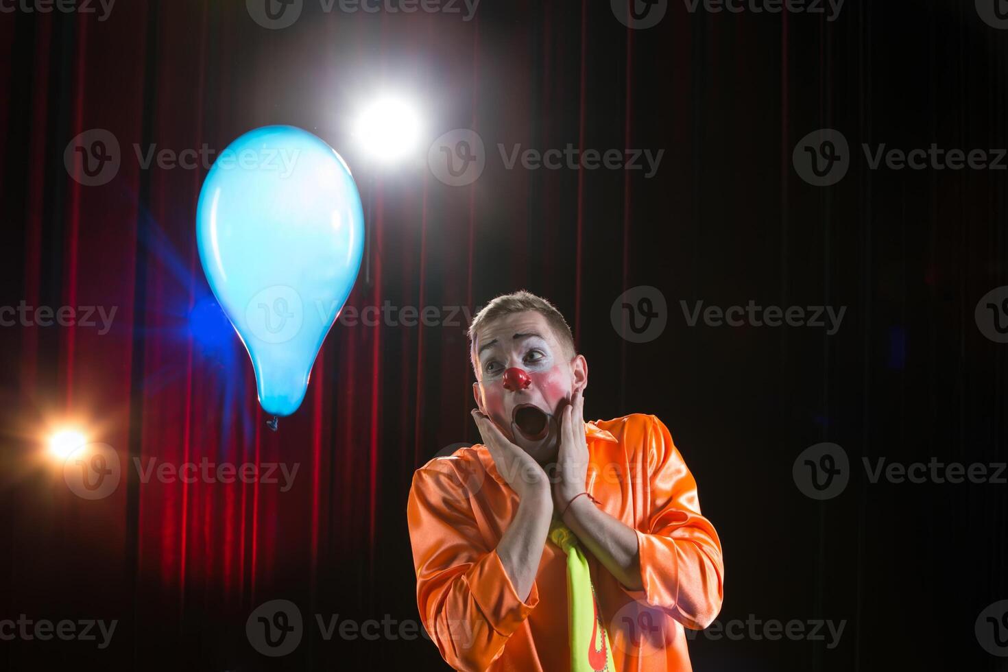 Circus clown performs number. A man in a clown outfit with a toy  A man in a clown outfit with a balloon photo