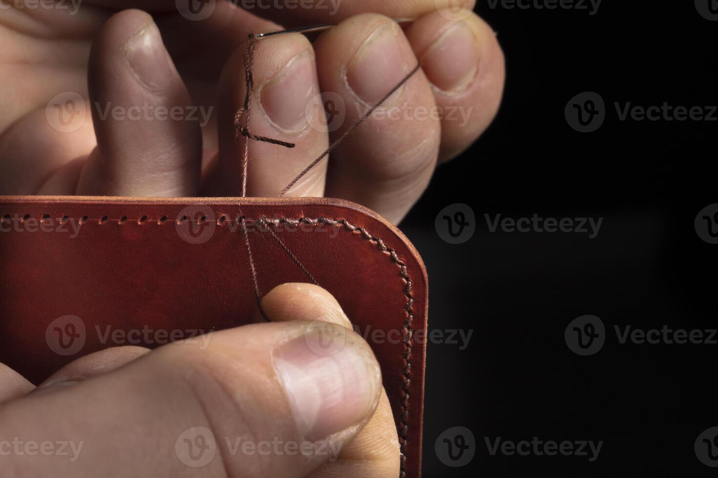 Making leather wallets. The hands of the master sew a leather product. photo