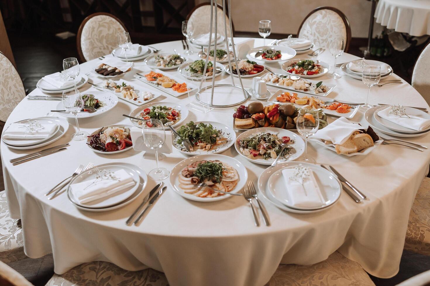 A view of wedding tables, attention to serving, with flower arrangements, expensive cutlery, plates with white napkins. photo