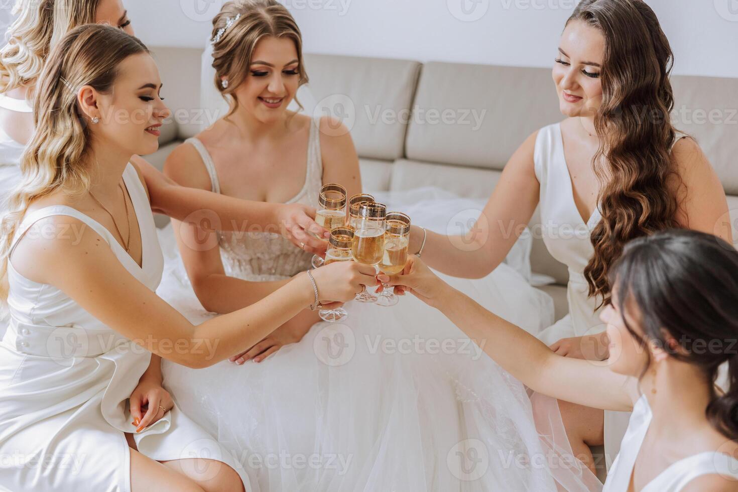 Photo bride with her friends drinking champagne from glasses. Cropped shot of a beautiful young bride and her bridesmaids having champagne before the wedding.