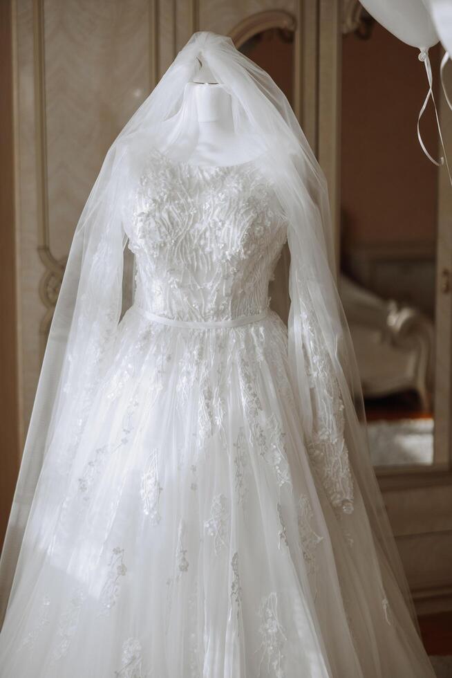 Bedroom interior with wedding dress prepared for the ceremony. A beautiful lush wedding dress on a mannequin in a hotel room. photo