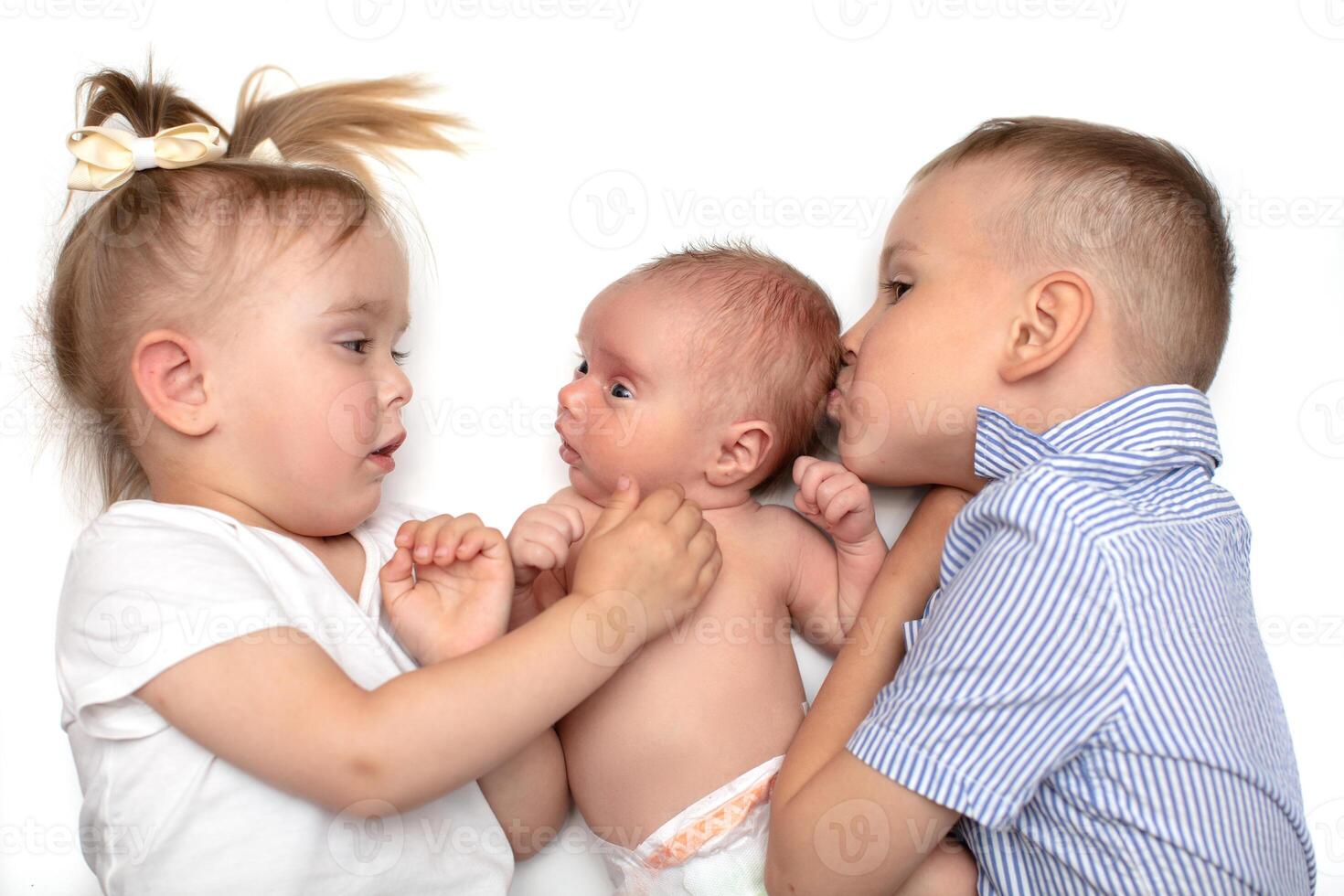 Closeup portrait of three cheerful kids lying down at home, newborn baby with brother and sister, happy family, love and friendship concept photo