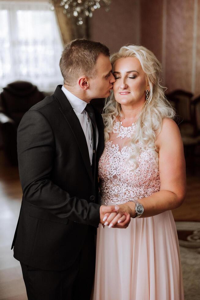 mother helps her adult son prepare for the wedding ceremony. An emotional and touching moment at a wedding. A mother hugs her son photo