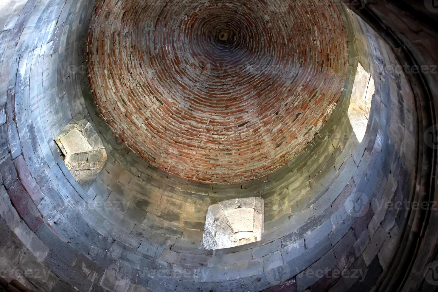 Roof of an ancient stone church with small windows and rays of light. photo