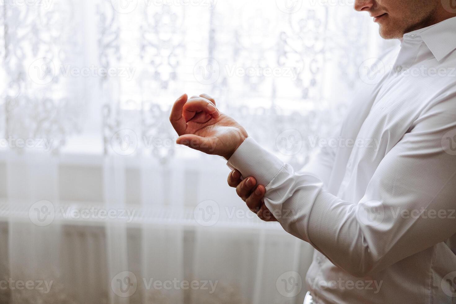 manos botón arriba el botones en su camisa. el proceso de fijación el botones en su blanco camisa. cerca vista. novio botones en su camisa puños Mañana de el novio foto