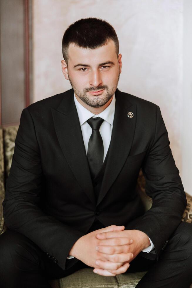 Portrait of a young groom at home before the wedding ceremony. A handsome man dressed in a classic suit. Male portrait. photo