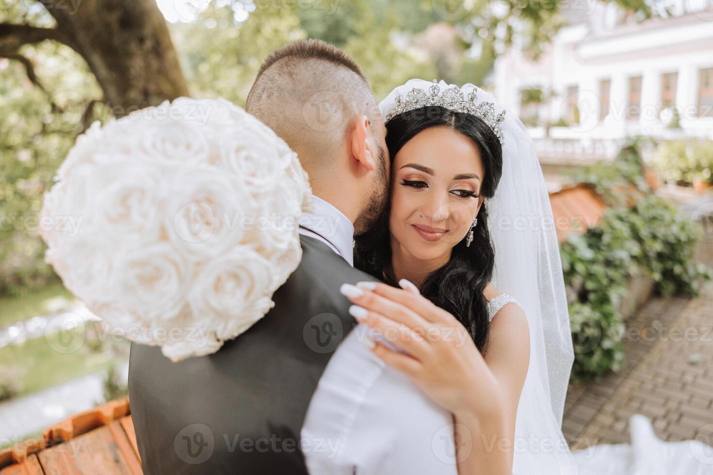 The groom kisses his bride on the temple against the background of beautiful nature on a summer day. Art. Selective focus. photo