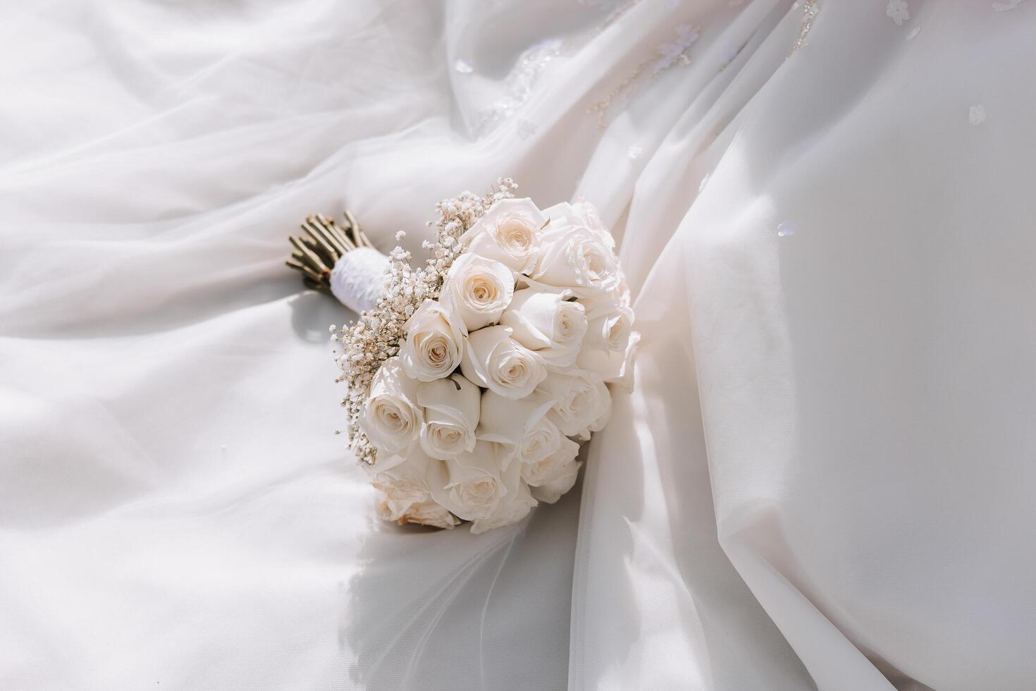 an elegant and beautiful wedding bouquet of white flowers lies on the bride's white dress. High quality photo