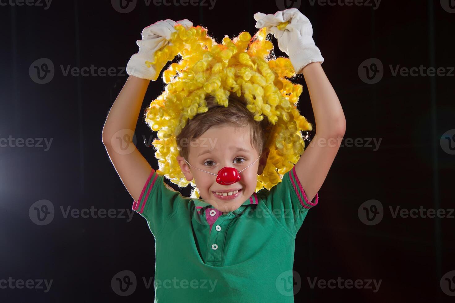 pequeño chico payaso. niño en un payaso peluca con un rojo nariz cerca arriba foto