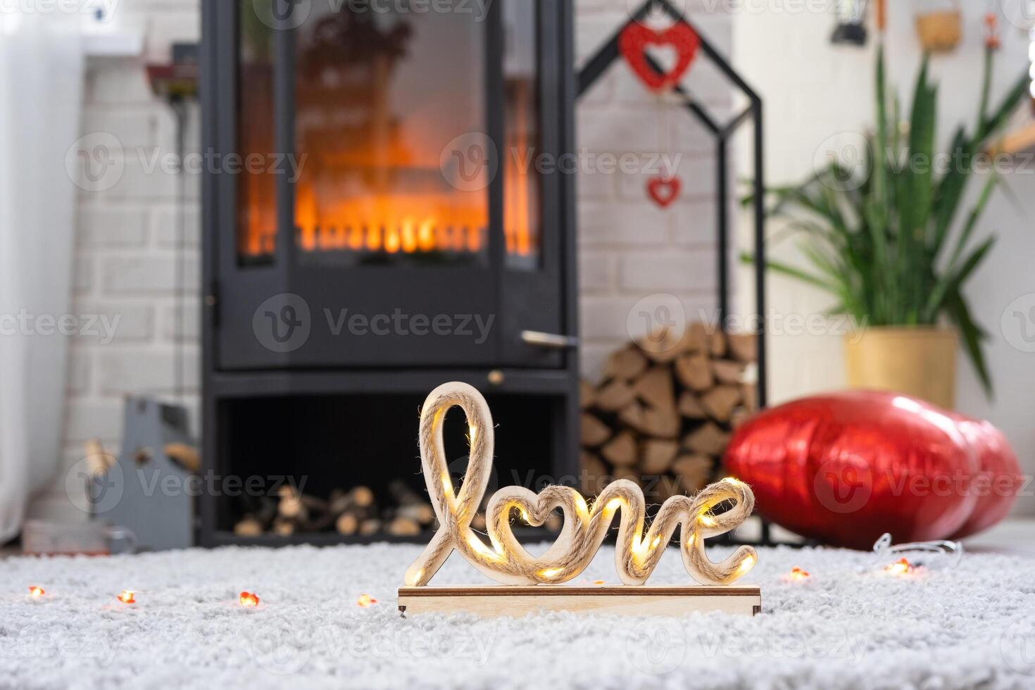 Key to house with keychain against background of fireplace stove with fire and firewood in Valentine decor, love home. Moving to new house, mortgage, rent and purchase real estate photo