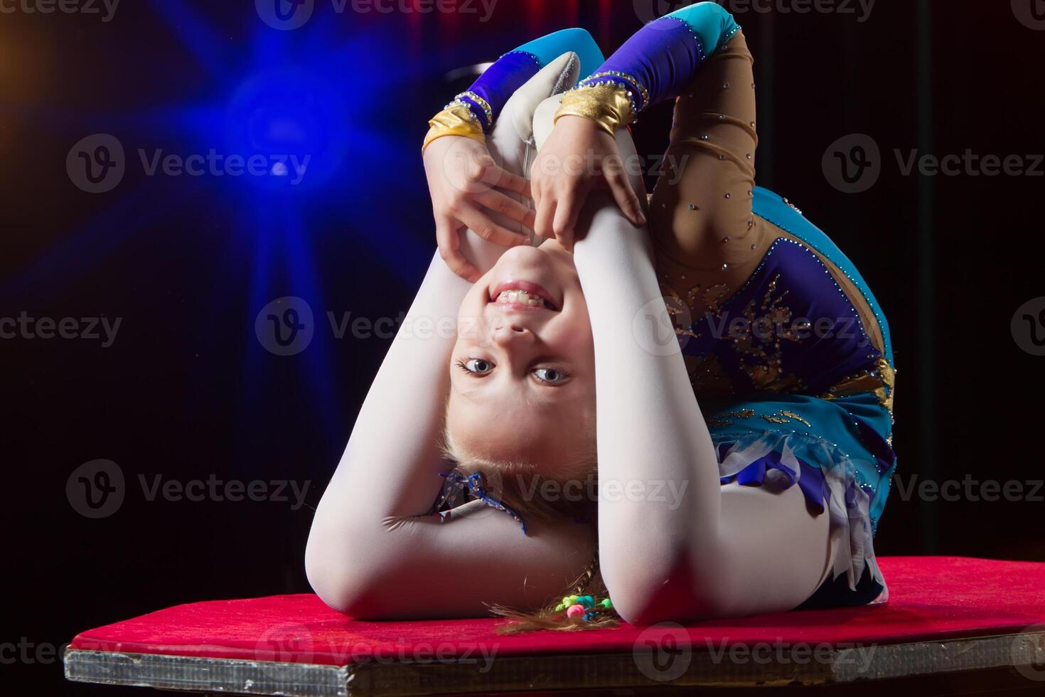 A girl with a flexible body. Performs a circus artist. Circus gymnast. Balancing act. The child performs an acrobatic trick photo