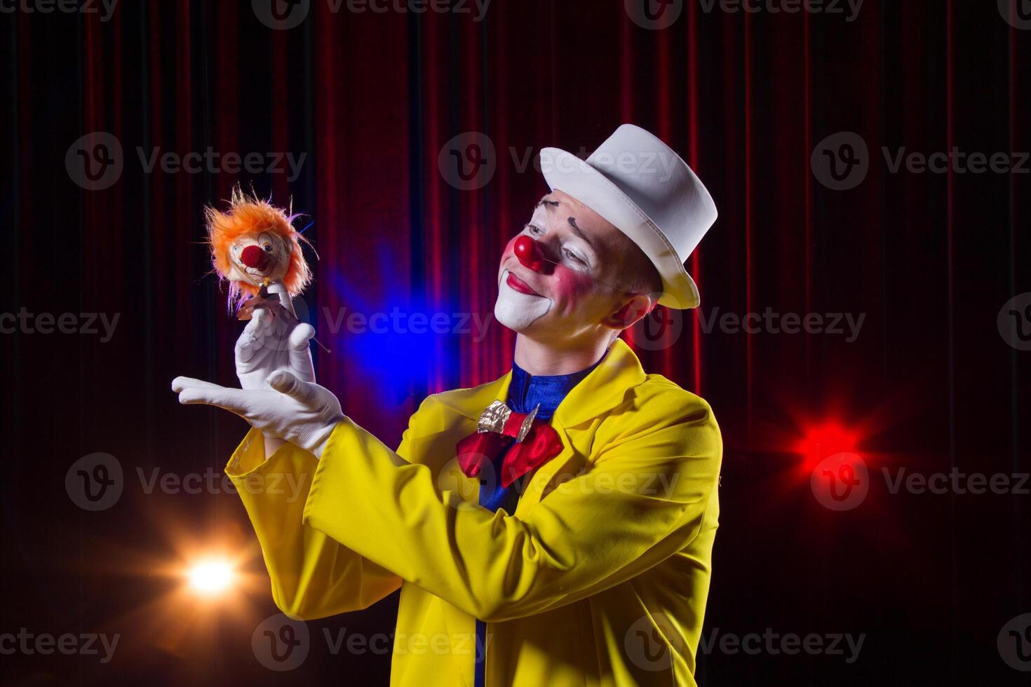 Circus clown performs number. A man in a clown outfit with a toy photo