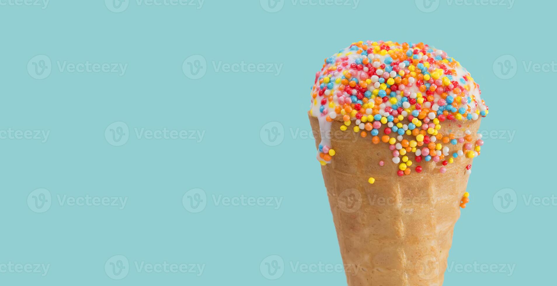 Ice cream cone close up. White ice cream scoop in a waffle cone on a blue background. Sweet dessert decorated with multicolored sprinkles photo
