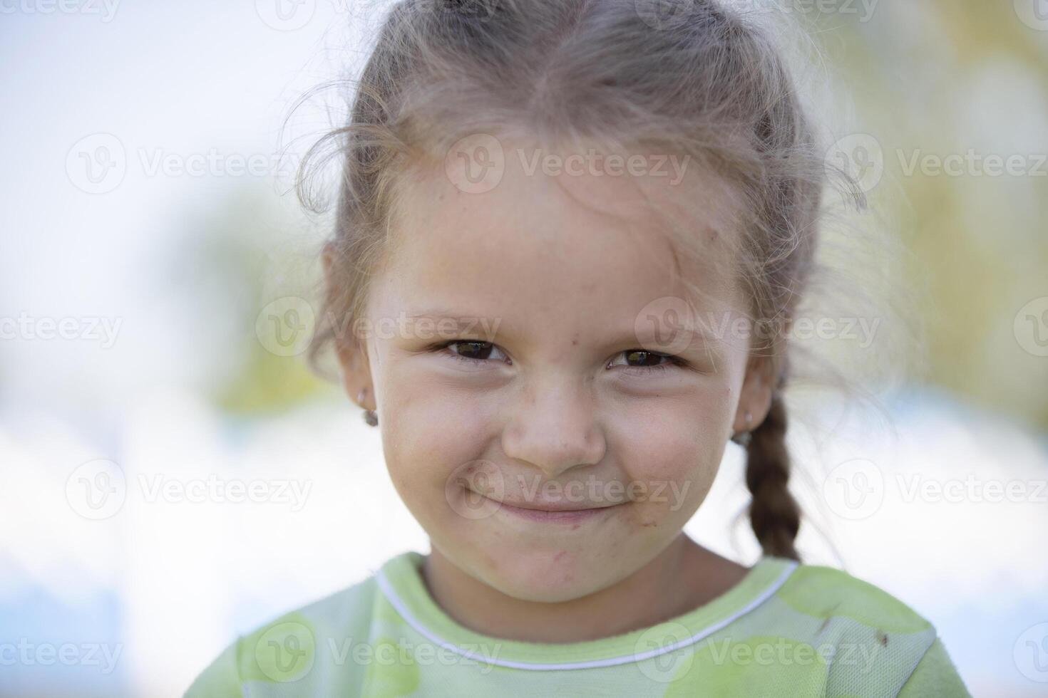 A funny girl with a dirty face looks at the camera and smiles. photo