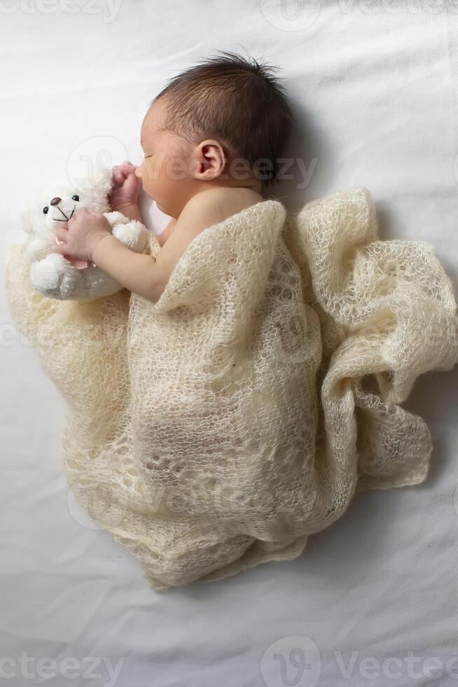 Newborn baby wrapped in a knitted blanket on a light background. photo