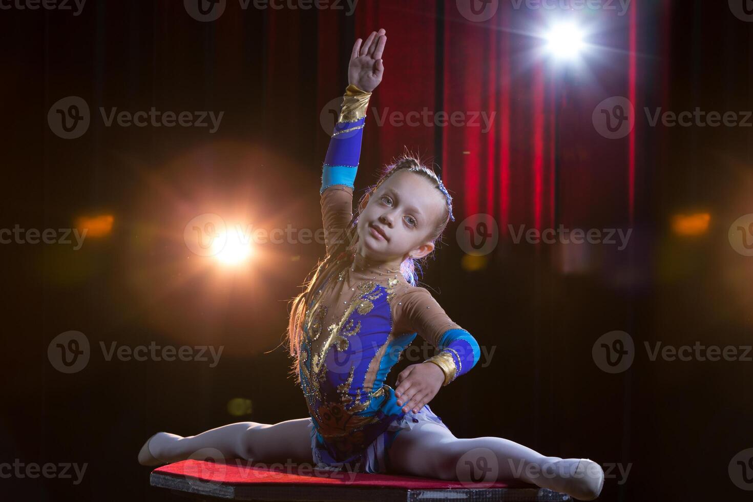 un niña con un flexible cuerpo. realiza un circo artista. circo gimnasta. equilibrio acto. el niño realiza un acrobático truco foto