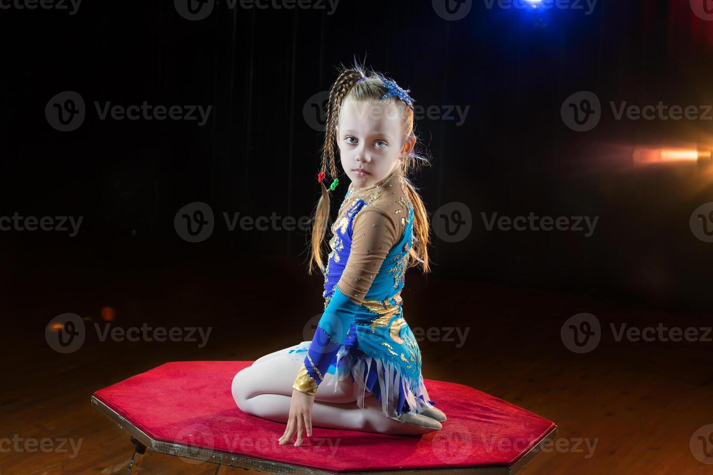 pequeño niña gimnasta se sienta en el mesa foto