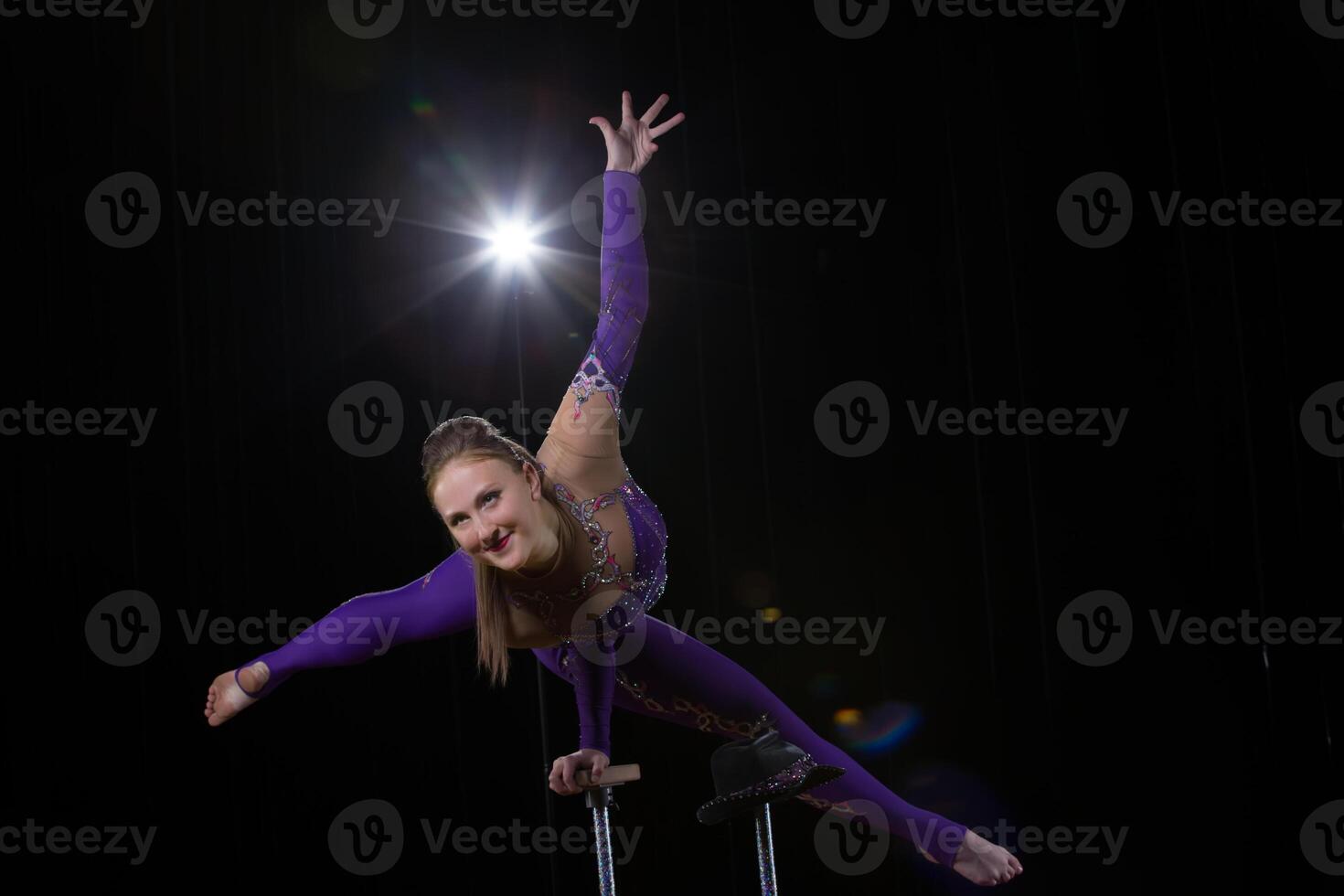 circo Actriz realiza el número en un hermosa fumar. manual equilibrio en bastones flexible niña cuerpo.rendimiento de un aire gimnasta en un circo foto