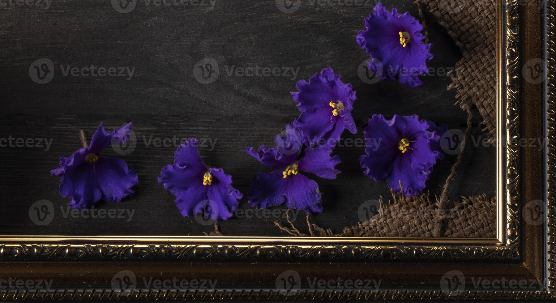 Part of a beautiful frame contains rough weave fabric on a wooden background and violet flowers. Background for the inscription. photo