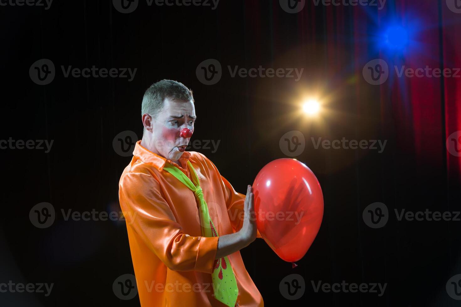 Circus clown performs number. A man in a clown outfit with a toy. A man in a clown outfit with a balloon photo