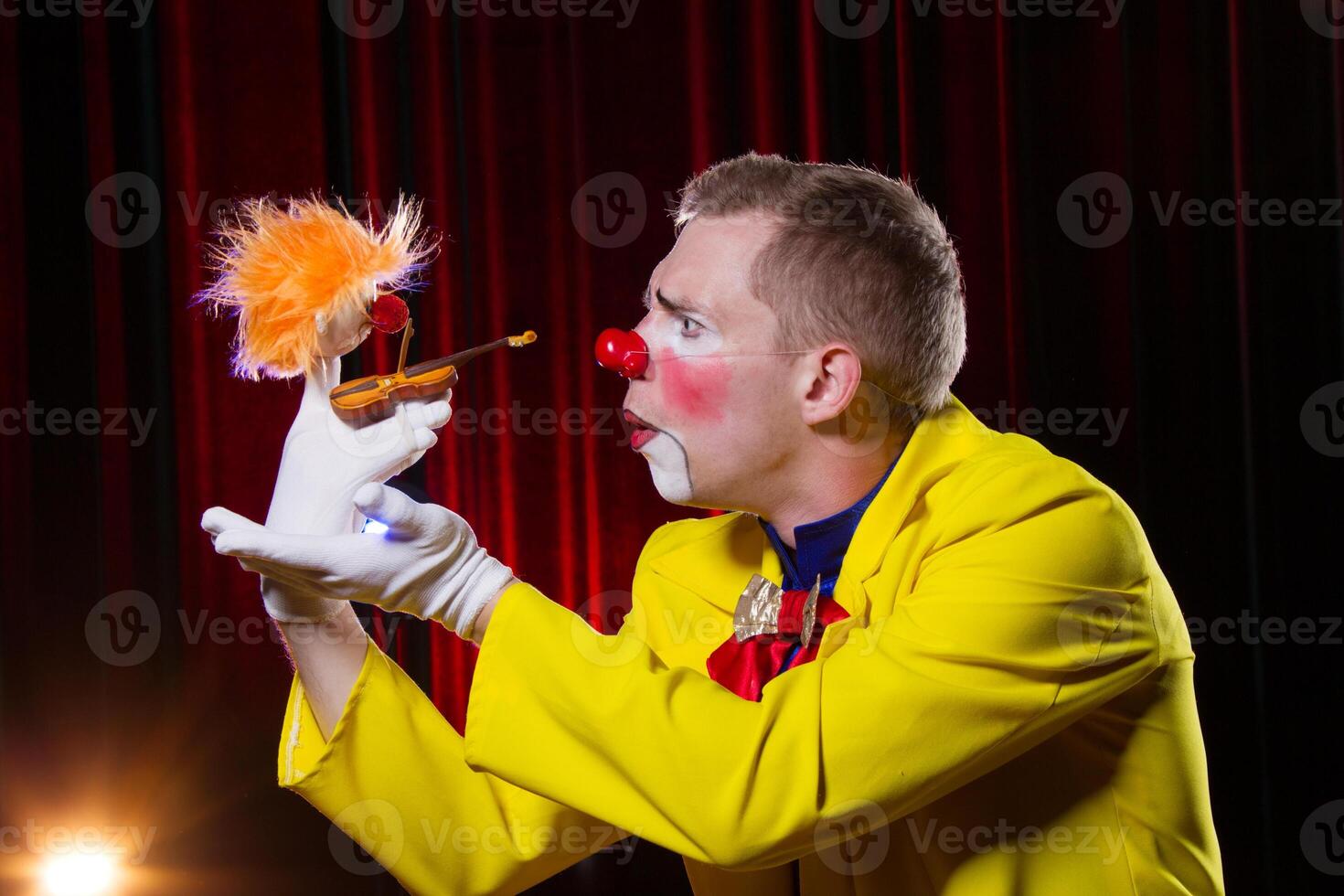 circo payaso realiza número. un hombre en un payaso atuendo con un juguete foto