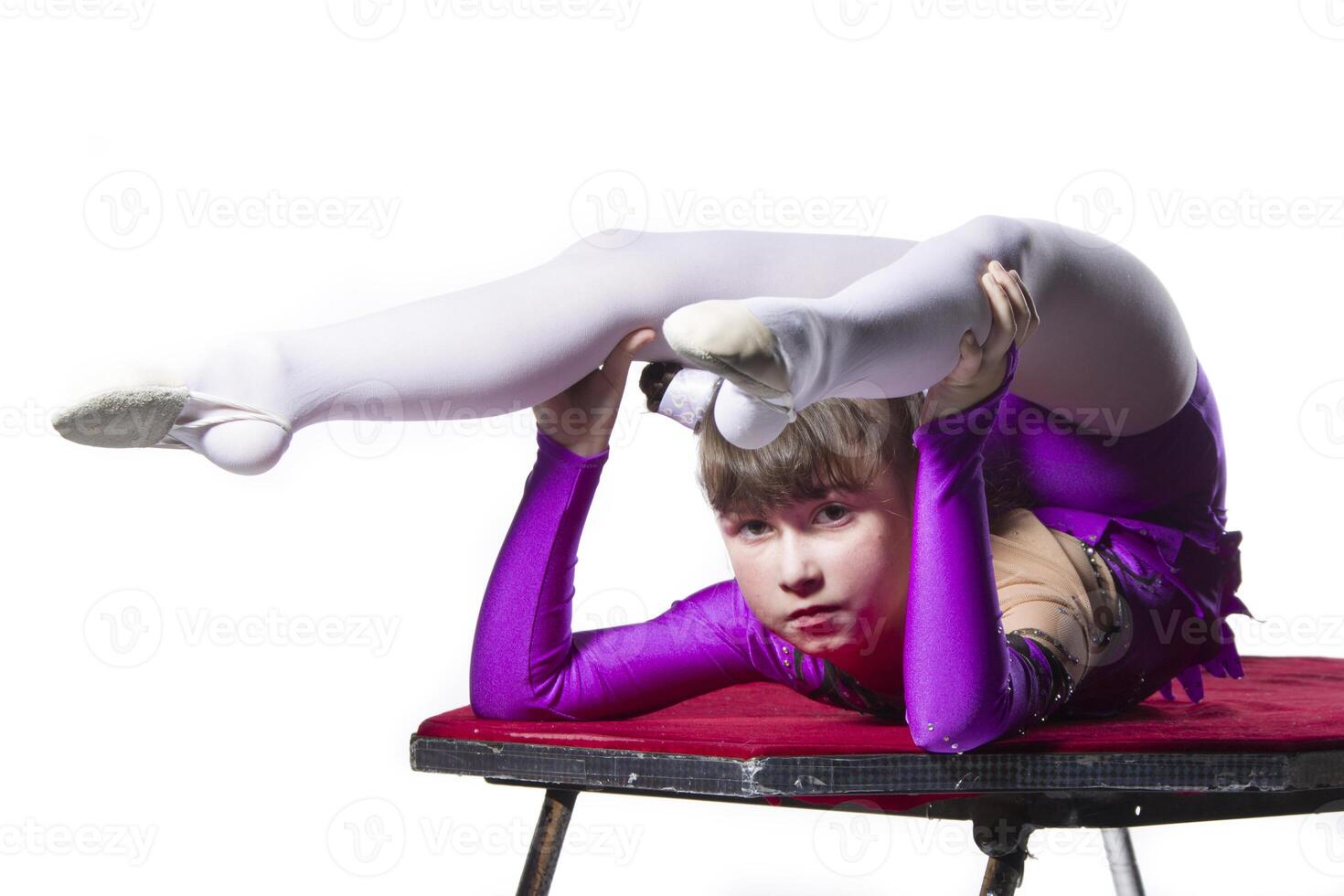 un niña con un flexible cuerpo. realiza un circo artista. circo gimnasta. equilibrio acto. el niño realiza un acrobático truco en un blanco antecedentes foto